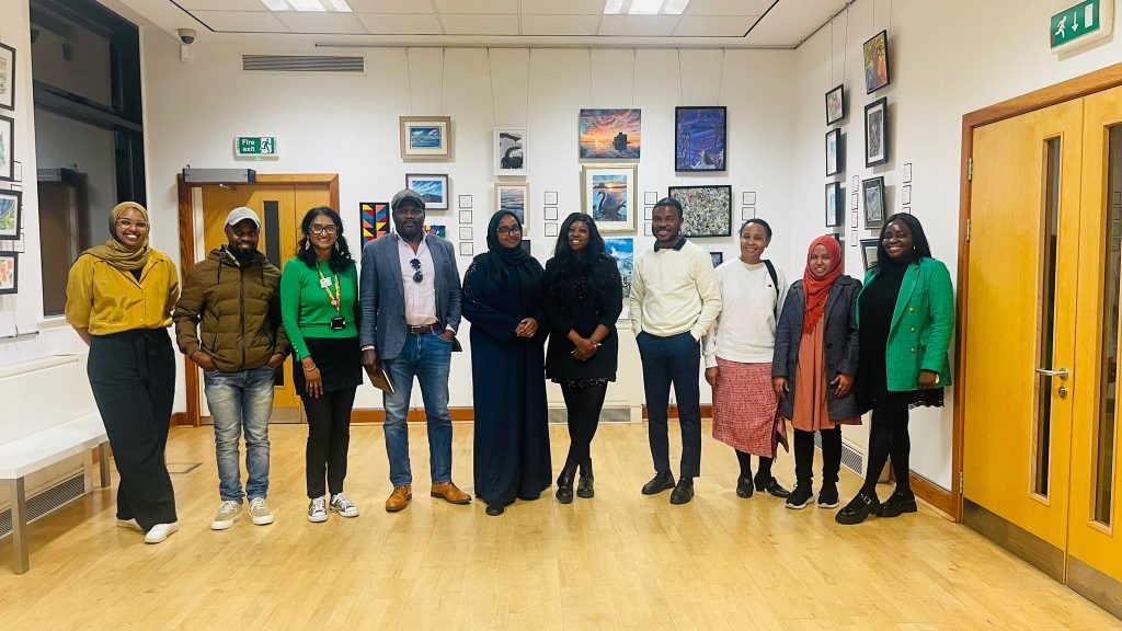 A gathering of individuals in a room filled with framed pictures, creating a warm and inviting atmosphere.