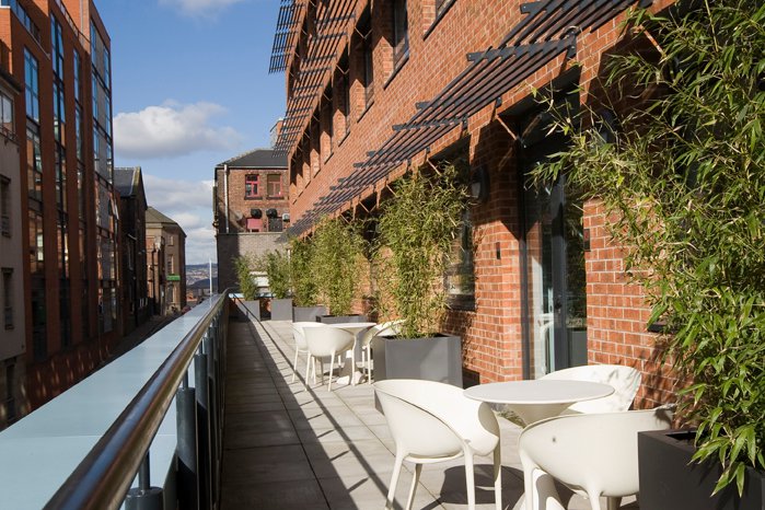 A balcony featuring white chairs and tables, creating a serene outdoor seating area.