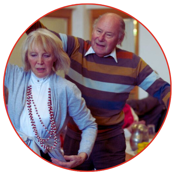 An older couple joyfully dancing together in a warmly lit room