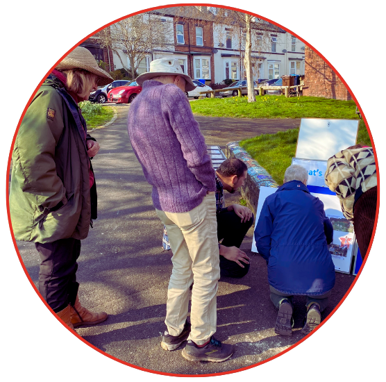 A diverse group of individuals gathered around a map spread on the ground, engaged in discussion and planning.